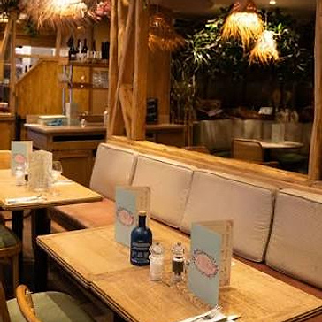 Le Village Café dining room: light banquette, wooden tables and woven pendant lamps